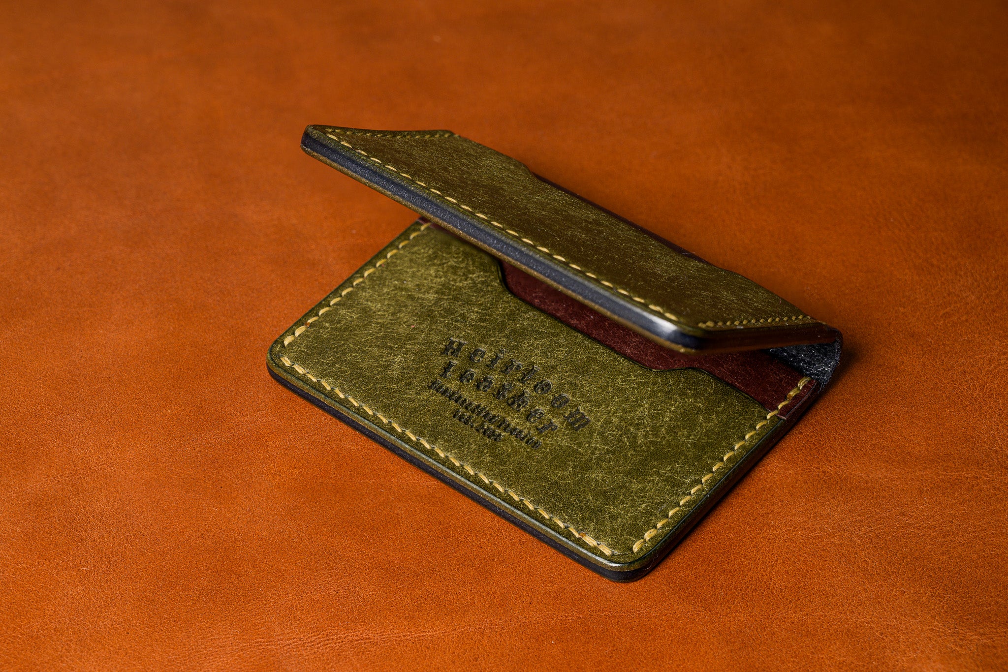 Green leather cardholder on a brown leather background