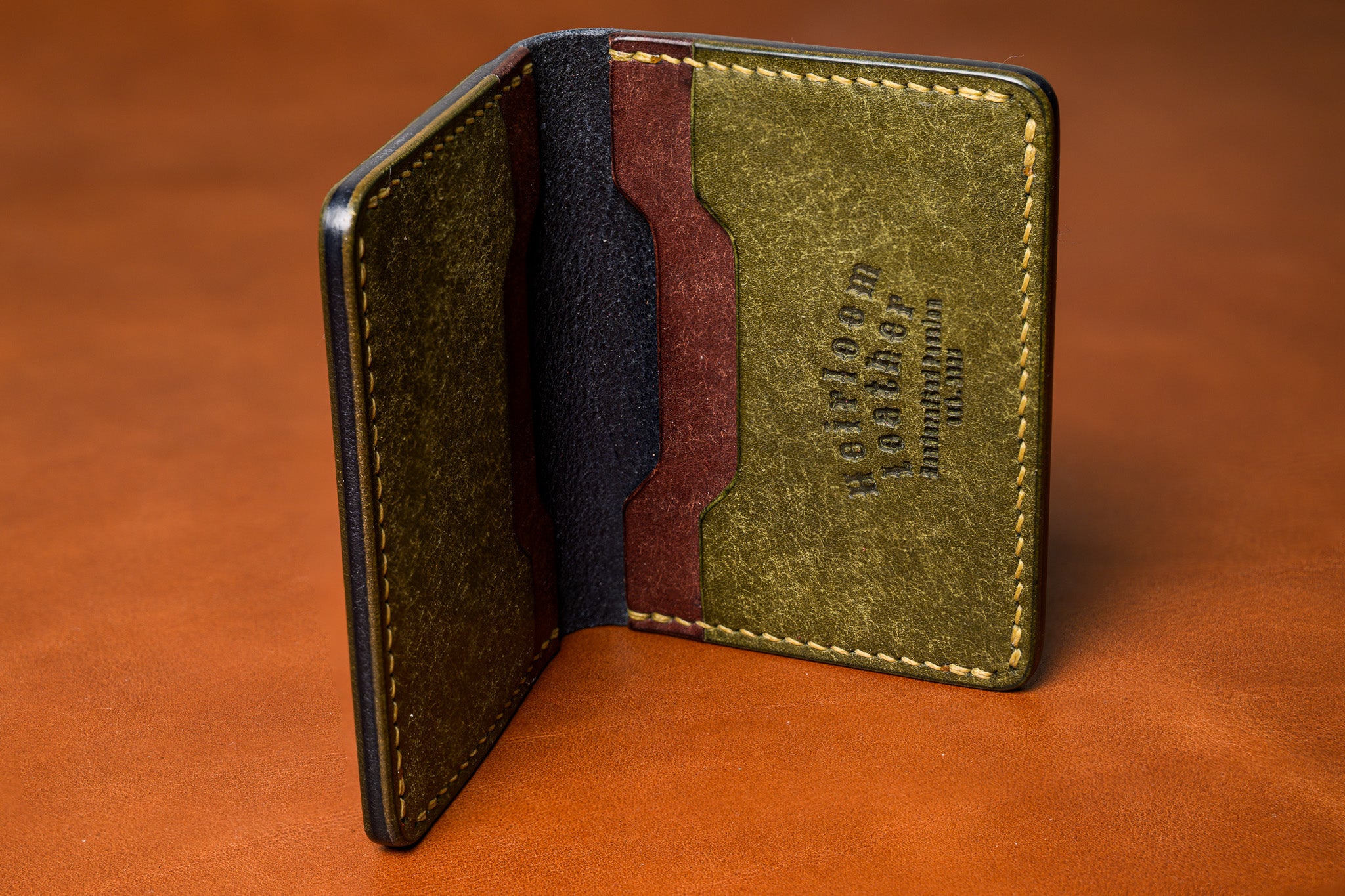 Green leather wallet with stitching details on a brown background