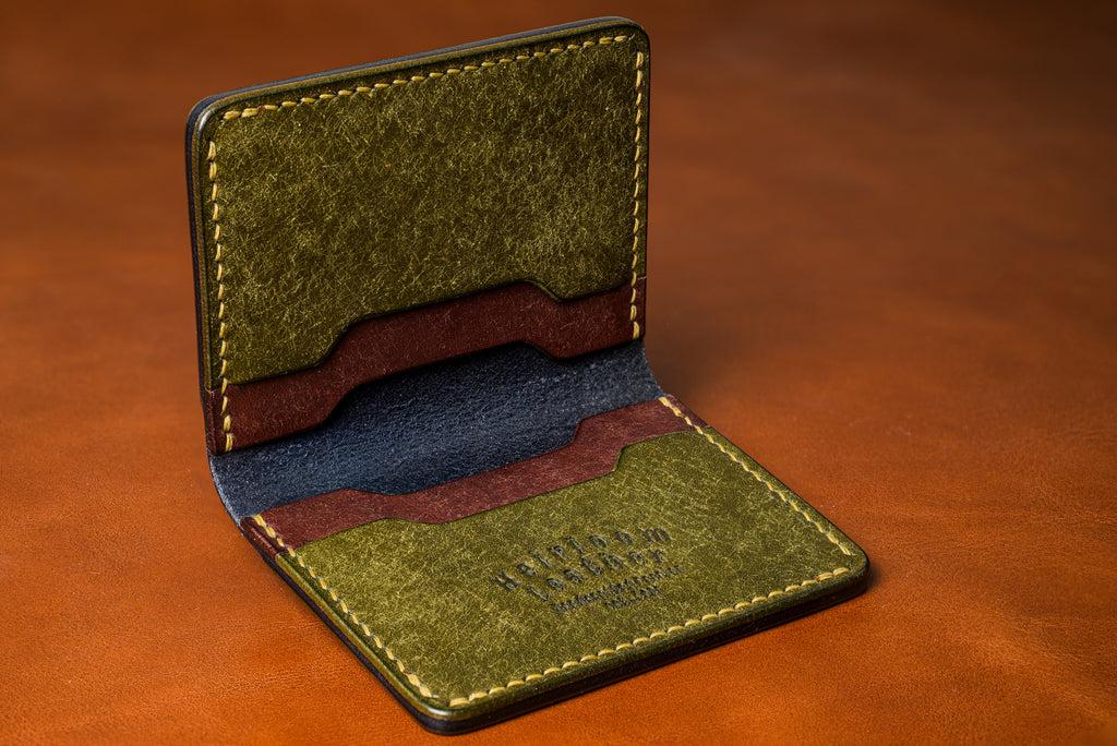 Green leather wallet with brown accents on a brown background
