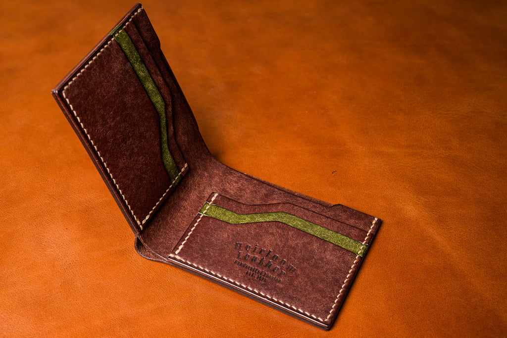 Brown leather wallet with green accents on a matching brown background