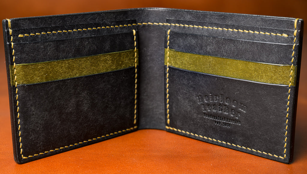 Black leather wallet with green accents on a brown background
