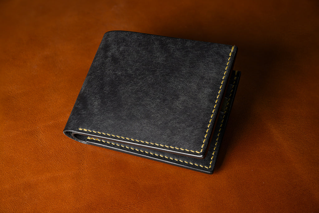 Black leather wallet on a brown leather background