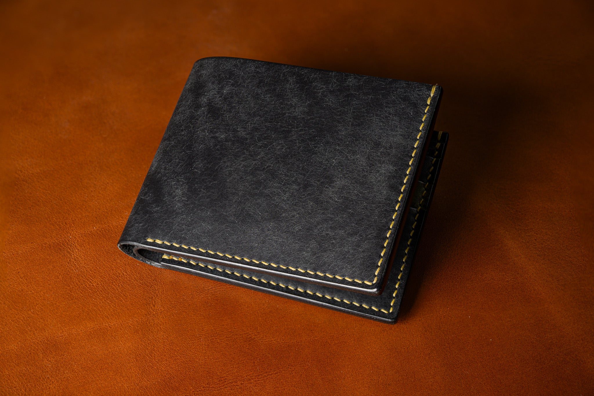 Black leather wallet on a brown leather background