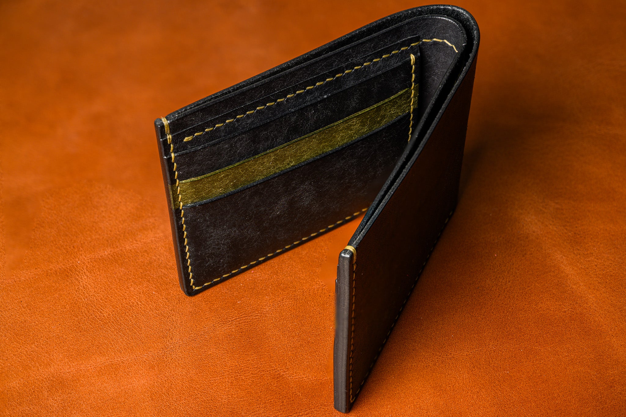 Brown leather wallet with gold stitching on a matching brown background