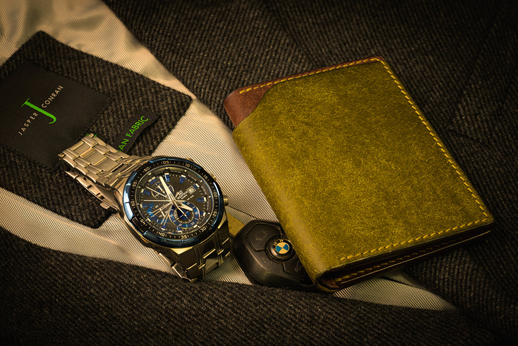 Watch, wallet, and car key on a textured surface