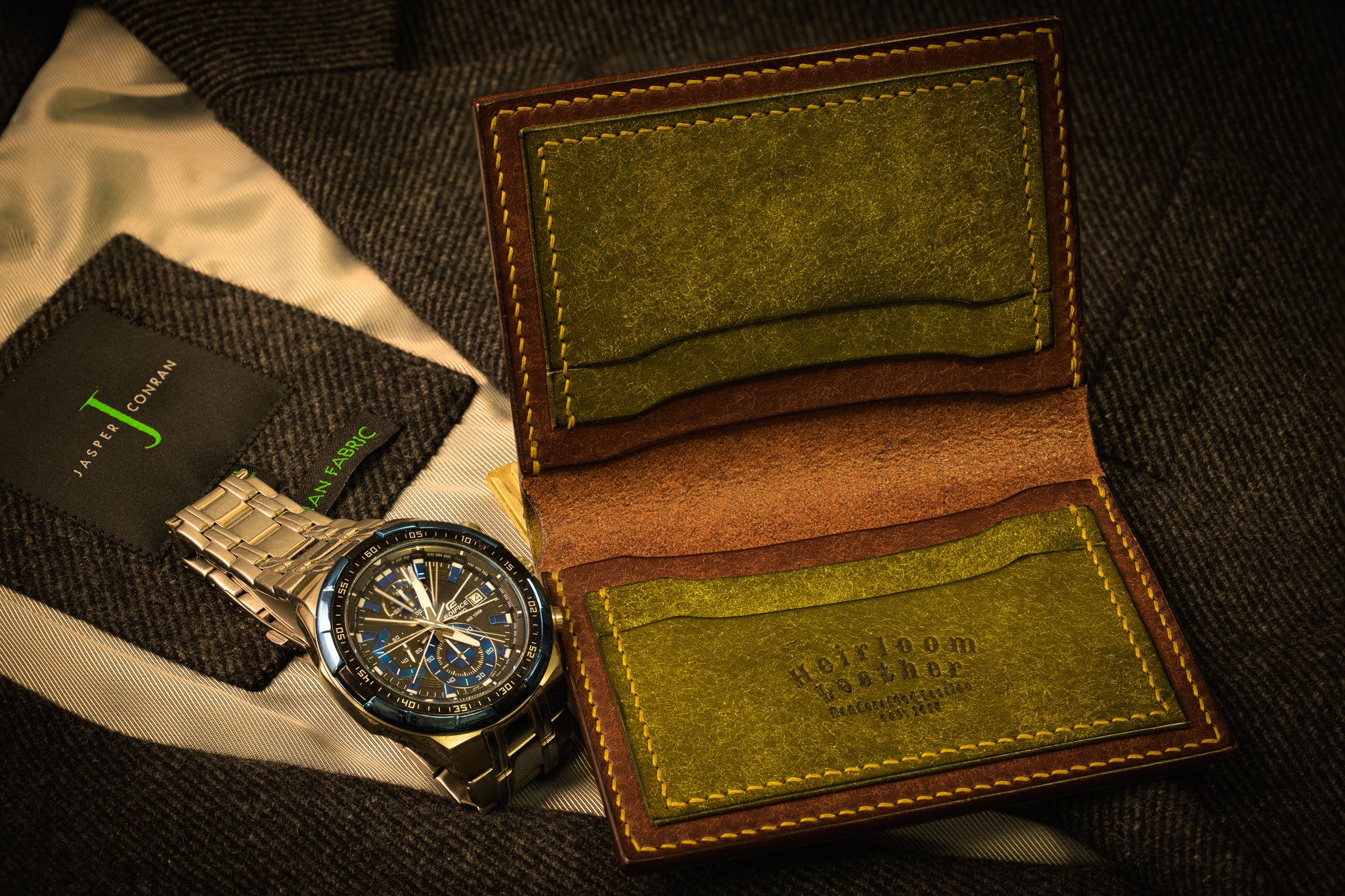 Watch and green leather wallet on a textured surface