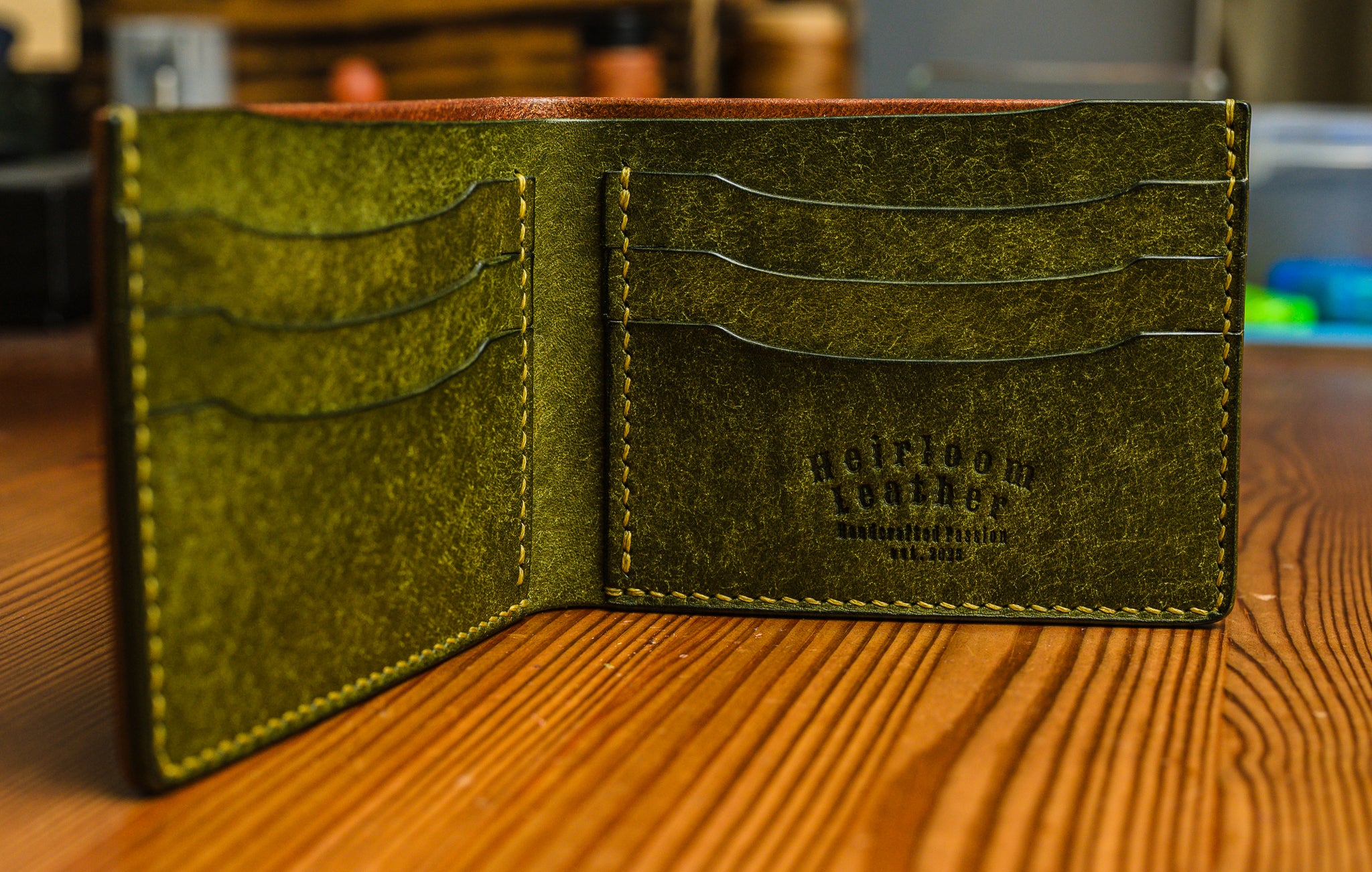 Green leather wallet with visible branding on a wooden surface