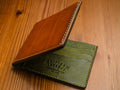 Tan leather wallet with Olive interior on a wooden surface