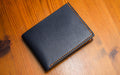 Navy leather wallet with brown stitching on a wooden surface