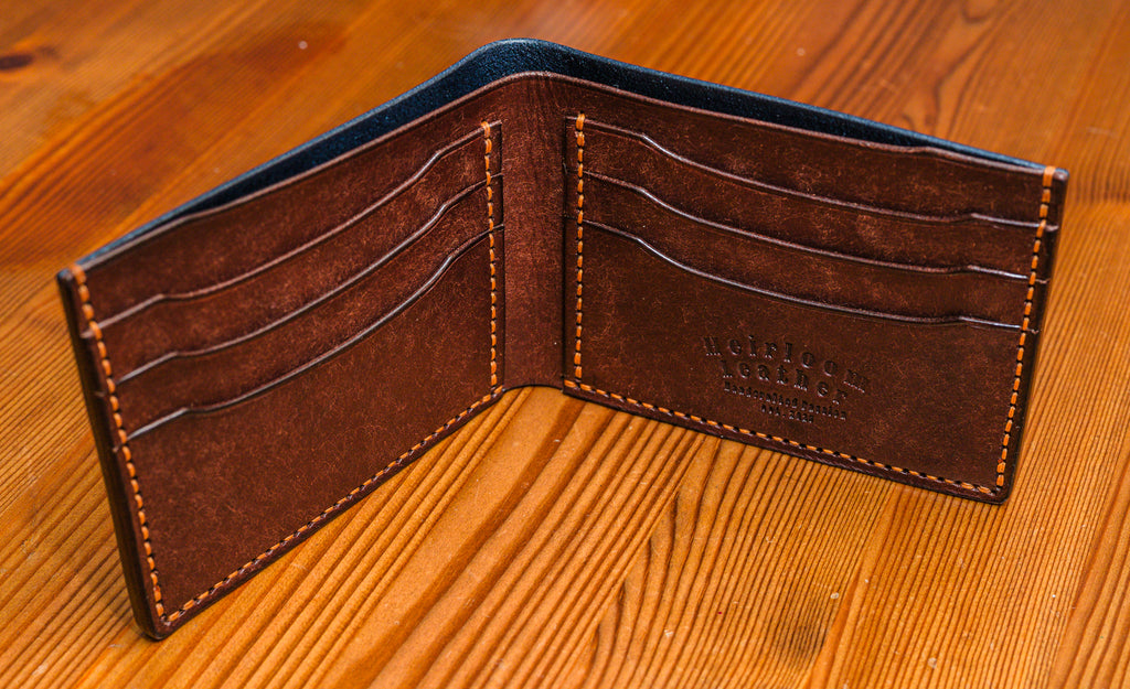 Pueblo leather wallet with visible stitching on a wooden surface