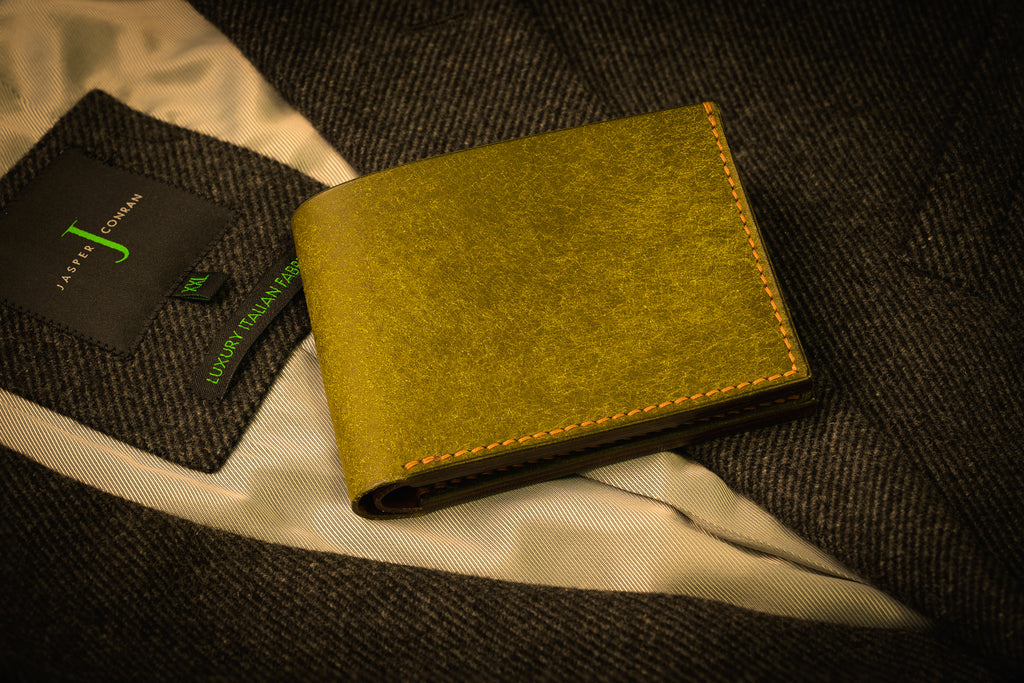 Green wallet on a textured surface with a brand card in the background