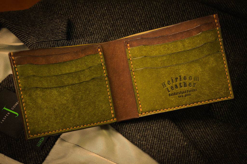 Open leather wallet with green interior and visible brand name on a textured surface