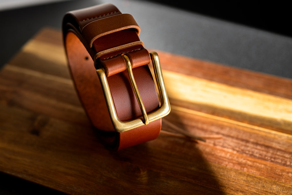 Brown leather belt with gold buckle on a wooden surface