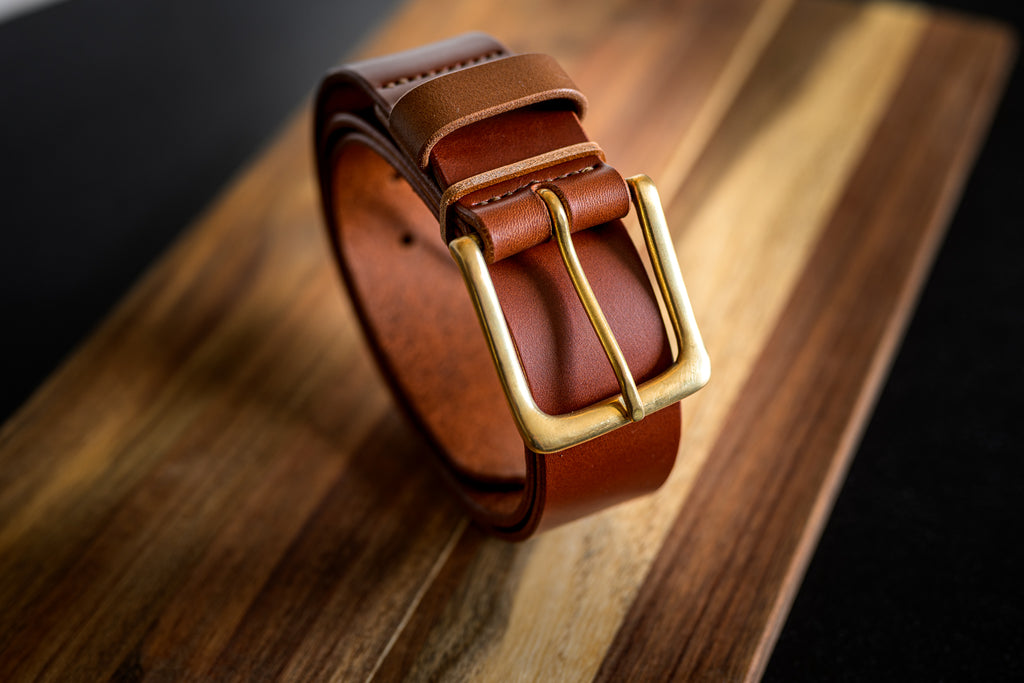 Brown leather belt with gold buckle on a wooden surface