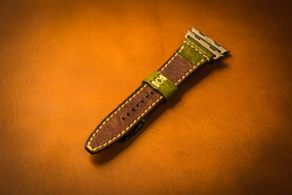 Brown leather watch strap with green interior on a brown background