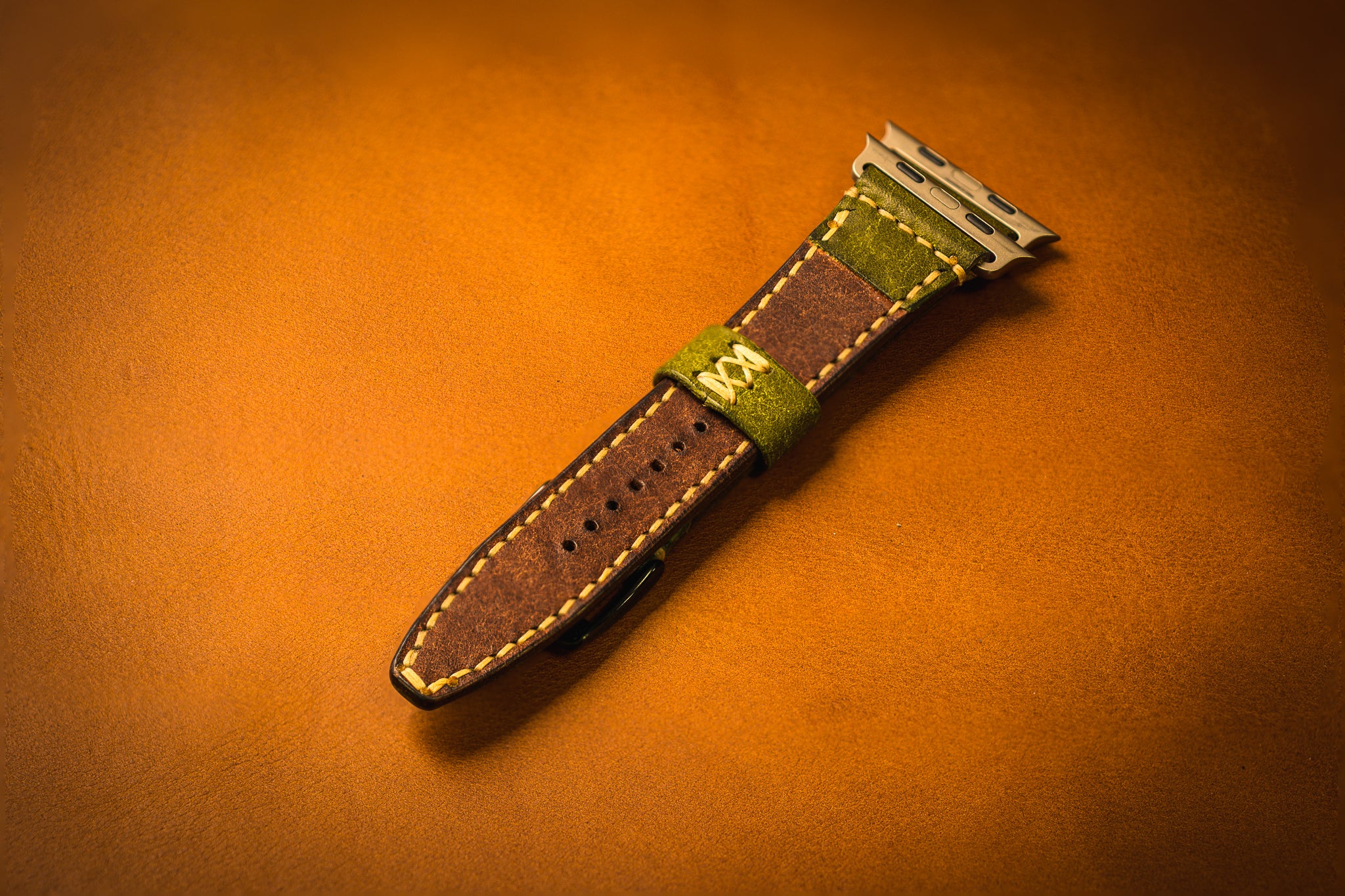 Brown leather watch strap with green interior on a brown background