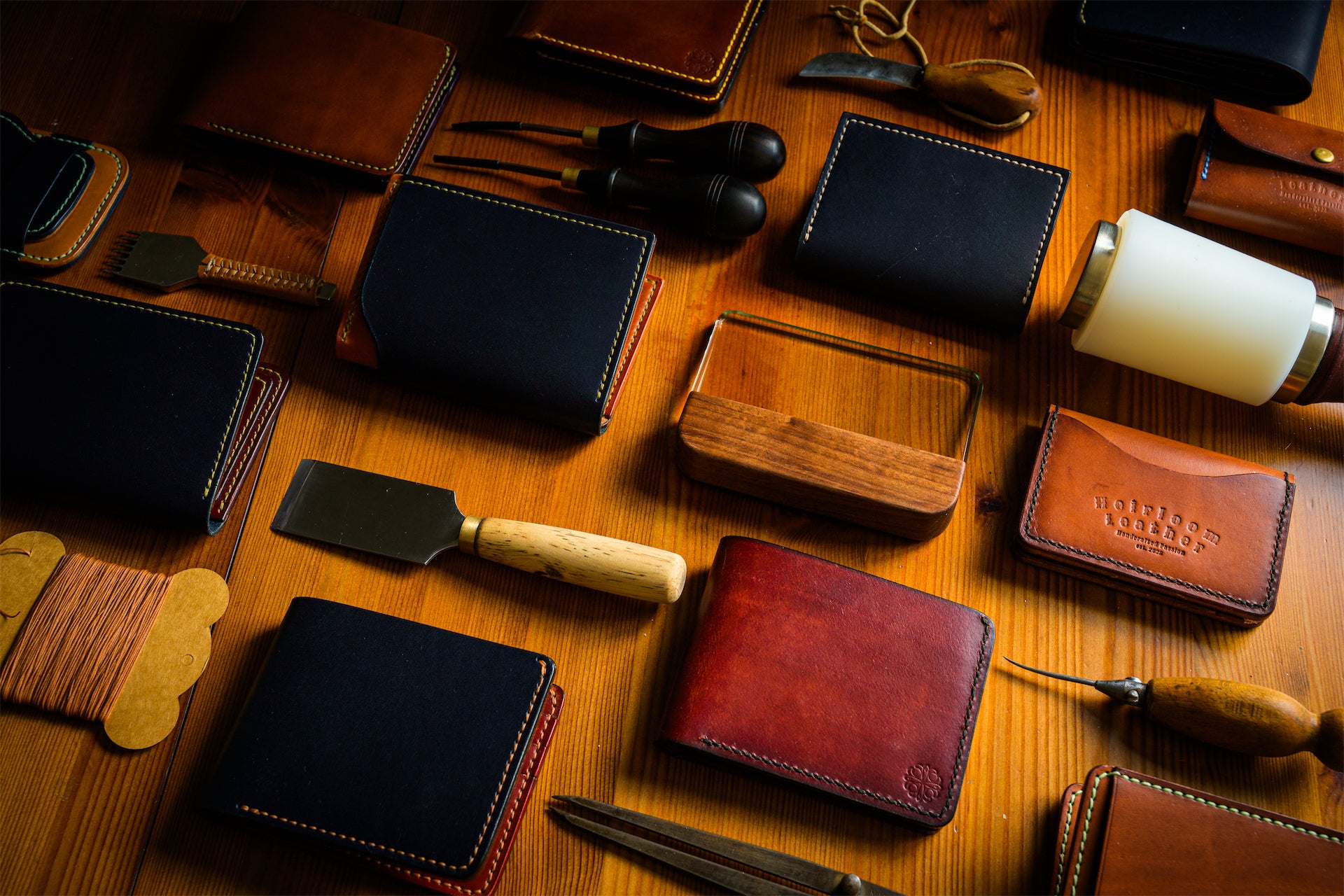 Collection of leather wallets and tools on a wooden surface